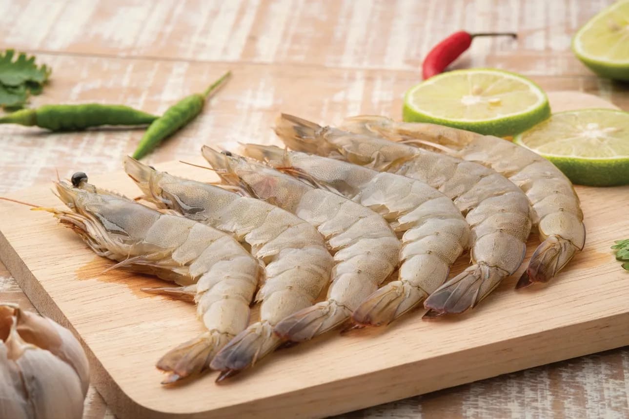 Ahşap tahtada biber ve limonla beyaz karidesler